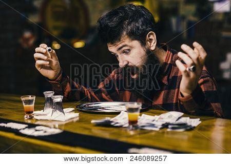 Get High And Dope Concept. Guy Holds Rolled Banknote, Defocused Background. Hipster With Beard Sniff