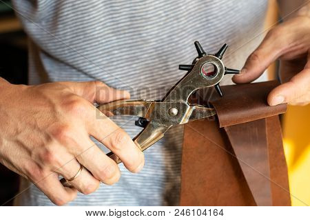 Making Holes With Puncher In Leather Workshop. Male Hands With Eyelet Puncher Working With Piece Of 