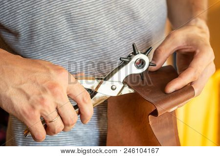 Making Holes With Puncher In Leather Workshop. Male Hands With Eyelet Puncher Working With Piece Of 