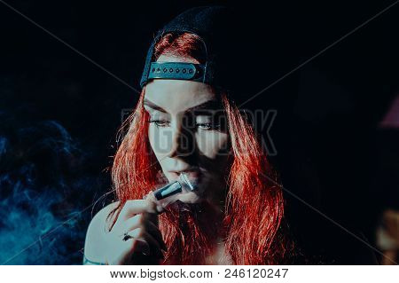 Red-haired Sexy Girl In A Cafe Dressed In Swimsuit Smoking A Hookah. Toned Image. Concept Of Pleasan