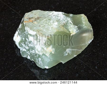Macro Shooting Of Natural Mineral - Crystal Of Prase (green Quartz) Stone On Black Granite From Ural