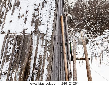 Old Typical Tools ( Ice Picks And Ladles) Near Closed Well In Russian Village In Overcast Winter Day
