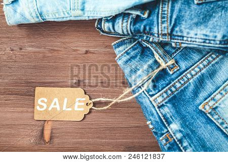 Concept Sales, Black Friday Discounts With Tag, Blue Jeans On A Wooden Background Copyspace. Flat La