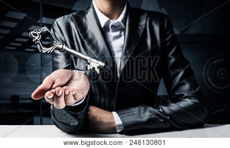 Cropped Image Of Businessman In Suit Keeping Big Key In Hand With Office View On Background.