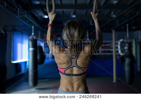 Young Woman Doing A Pullup Ongymnastic Rings, In The Gym.
