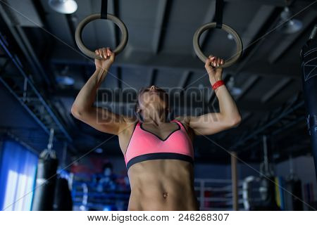 Young Woman Doing A Pullup Ongymnastic Rings, In The Gym.