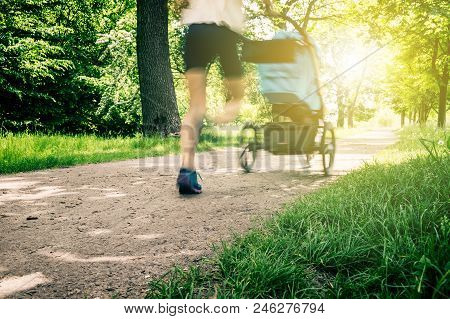 Running Woman With Baby Stroller Enjoying Summer In Park. Jogging Or Power Walking Supermom, Active 