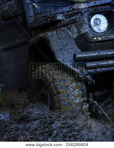 Extreme Entertainment Concept. Offroad Tire Covered With Mud Overcomes Obstacles On Nature Backgroun