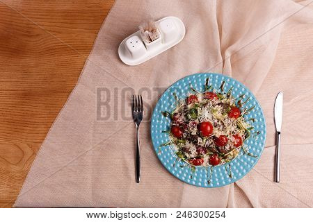A Plate With Caesar Salad Is Layed Out On The Table, Covered With The Beige Table Cloth.