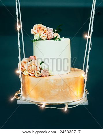 Wedding Cake On Decorative Swing, Decorated With Fowers And Luminous Garland