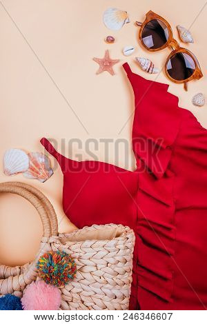 Summer Fashion Flatlay With Brown Sunglasses, Straw Bag With Pompoms And Red Swimsuit With Frills On