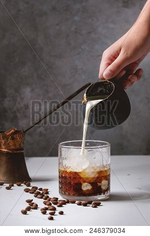 Iced Coffee Cocktail Or Frappe With Ice Cubes And Cream, Pouring From Jug, Served In Glass With Vint