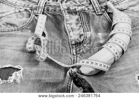 Health And Male Sexuality Concept. Banana Wrapped With Blue Measure Tape On Jeans, Selective Focus. 