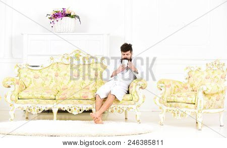 Elite Leisure Concept. Man With Beard And Mustache Enjoys Morning While Sitting On Luxury Sofa. Man 