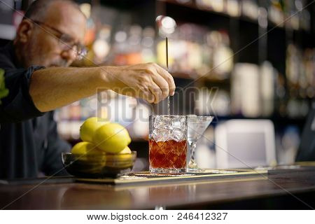 A Bartender Stirring Ingredients In A Mixing Glass In Order To Prepare And Serve A Chilled Cocktail 