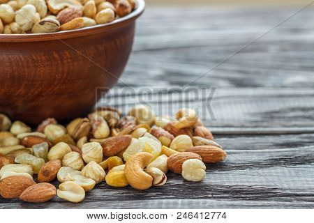 Mix Nuts In Earthenware On A Wooden Background.
