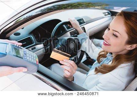 Smiling Businesswoman In Car Making Payment With Credit Card