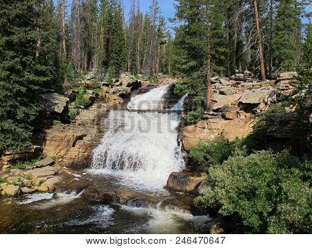 Natural Waterfall In High Uinta Mountains Of Utah With Evergreen Trees And Blue Sky