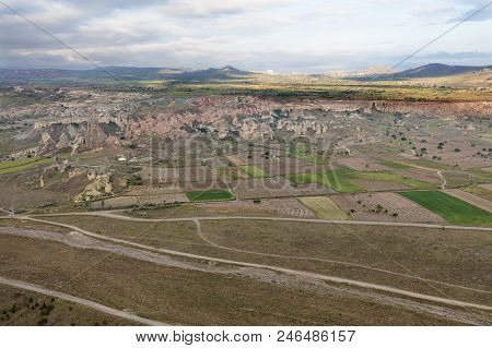 The Country Road Leads To The Village Through A Brown Valley And Fields Between The Mountains, A Vie