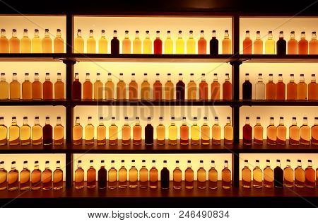 Unmarked Glass Whiskey Bottles Displayed On Backlit Shelves