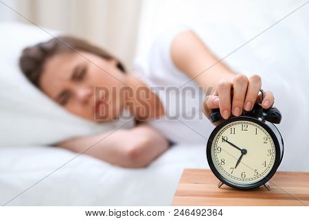 Sleepy Young Woman Stretching Hand To Ringing Alarm Willing Turn It Off. Early Wake Up, Not Getting 
