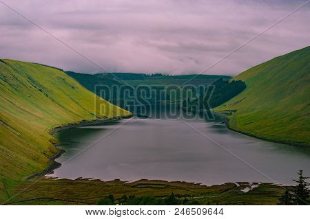 View Of A Beautlful Lake Talla In Scottish Borders With Green Hills Covered By Thick Rainy Clouds.