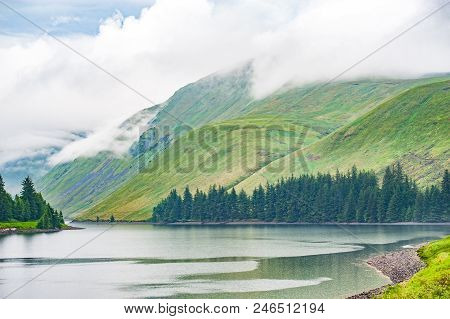 View Of A Beautlful Lake Talla In Scottish Borders With Green Hills Covered By Thick Rainy Clouds.
