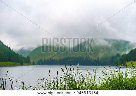 View Of A Beautlful Lake Talla In Scottish Borders With Green Hills Covered By Thick Rainy Clouds.