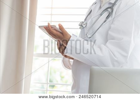 Healthcare Medical Concept : Asian Woman Doctor Standing Using Tablet Computer With White Gown Suite