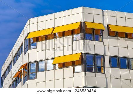 Detail Of Classic White And Black Hospital Building With Yellow Sunshades Under Blue Sky With High C