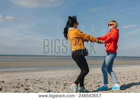 Happy Friends Holding Hands And Spinning On Sandy Beach, Saint Michaels Mount, Normandy, France