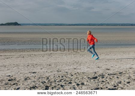 Stylish Young Woman Running On Sandy Beach, Saint Michaels Mount, France