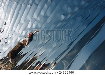 Wroclaw, Poland - 18 May 2018: Relaxed Young Woman In Front Of Sculpture Made Of Reflective Material