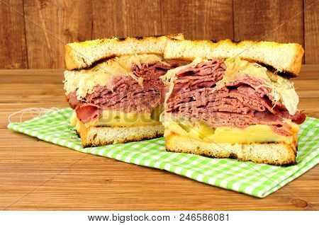 Pastrami Reuben style sandwich with sauerkraut and Swiss cheese on a wooden background