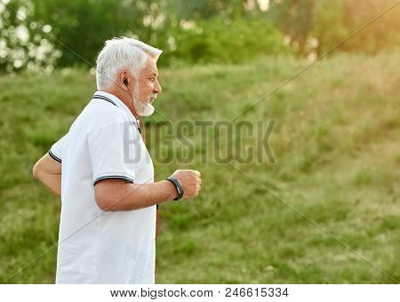 Running Old On Green Grass Background. Wearing Classic White Polo Shirt With Dark Blue Stripes, Spor