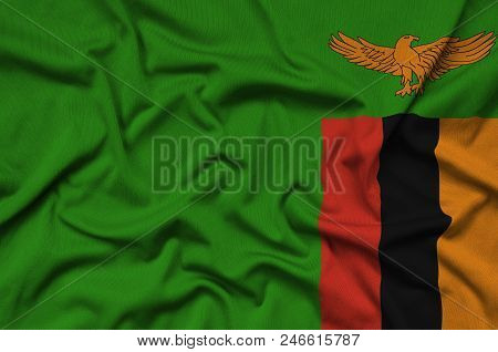 Zambia Flag  Is Depicted On A Sports Cloth Fabric With Many Folds. Sport Team Waving Banner