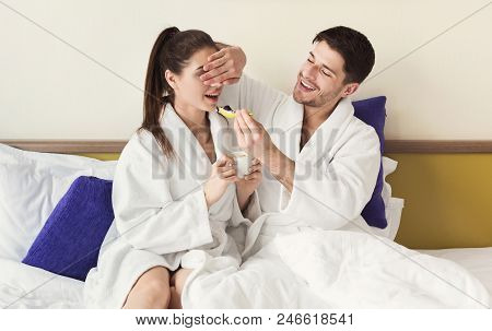 Loving Couple Having A Lazy Morning Breakfast In Comfortable Bed. Husband Feeding Wife