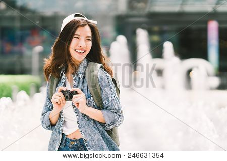 Young Beautiful Asian Backpack Traveler Woman Using Digital Compact Camera And Smile, Looking At Cop
