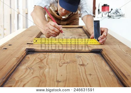 Carpenter At Work Measures With The Setsquare And Pencil On Wooden Board Background
