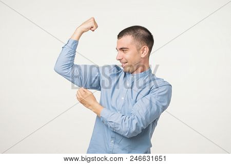 Handsome Middle Age Man In Blue Shirt Pointing Biceps Expressing Strength And Healthy Life. He Is St