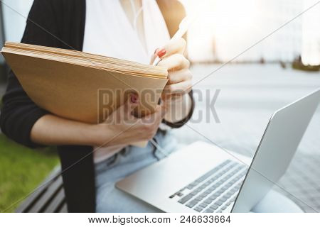 Young Student Woman Sits In City Park With Modern Laptop. Close-up Hands And Laptop. Business Woman 