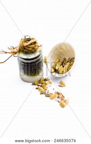 Green Colored Dry Fruit Essence Of Green Cardamom Or Elaichi Isolated On White In Transparent Bottle