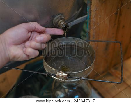A Human Finger Tasting Honey Pouring Throgh The Strainer Into A Jar