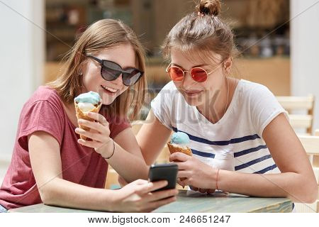 Glad Satisfied Female Companions Being Focused Ino Screen Of Modern Cell Phone, Watch Interesting Vi