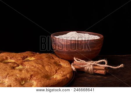 A Bowl With Flour And Apricot Cake On A Wooden Background On Black