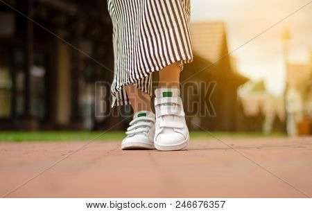 Female Legs In Street Sneakers Nature Sun Skyon Blur Background Beauty Fashion