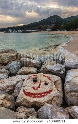 View of an empty beach with a smiling face painted on a stone in a overcast day
