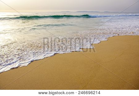 Golden sand with ocean water foam in the sea shore of a beach 