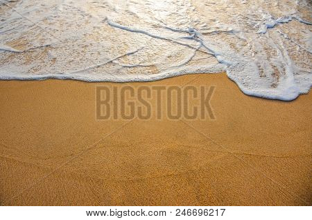 Golden sand with ocean water foam in the sea shore of a beach 