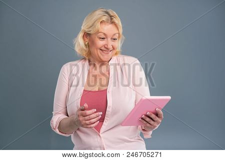 Mood-boosting News. Overjoyed Middle-aged Woman Beaming Having Read A Message On Her Tablet While St